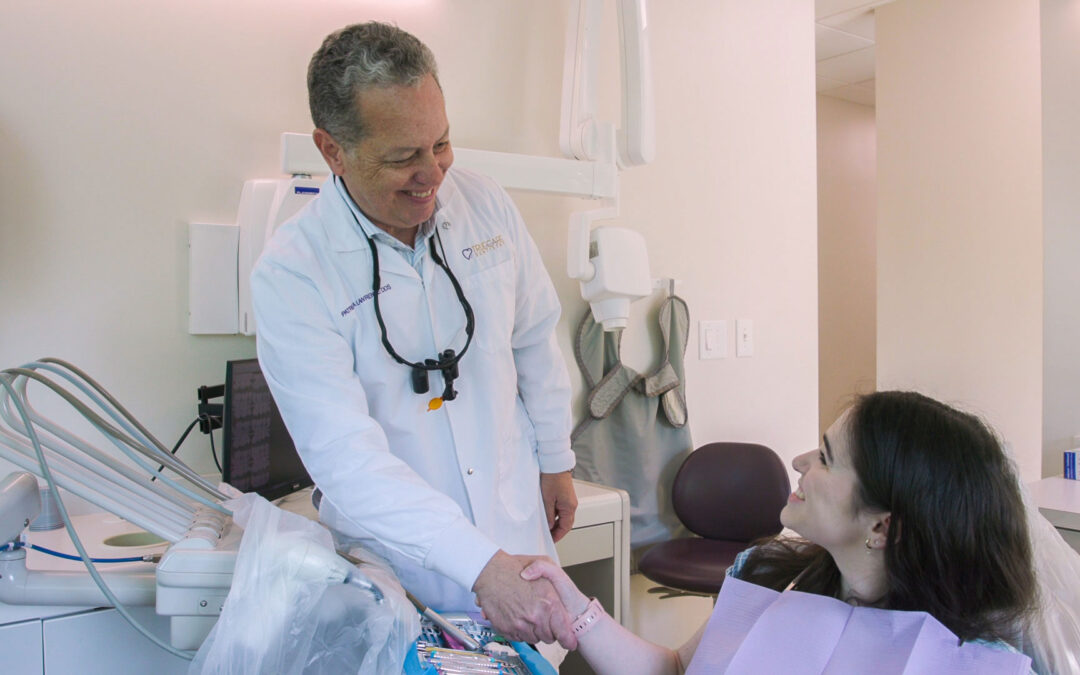 Dentist at TrueCare Dentistry shaking hands with a smiling patient in the exam room.