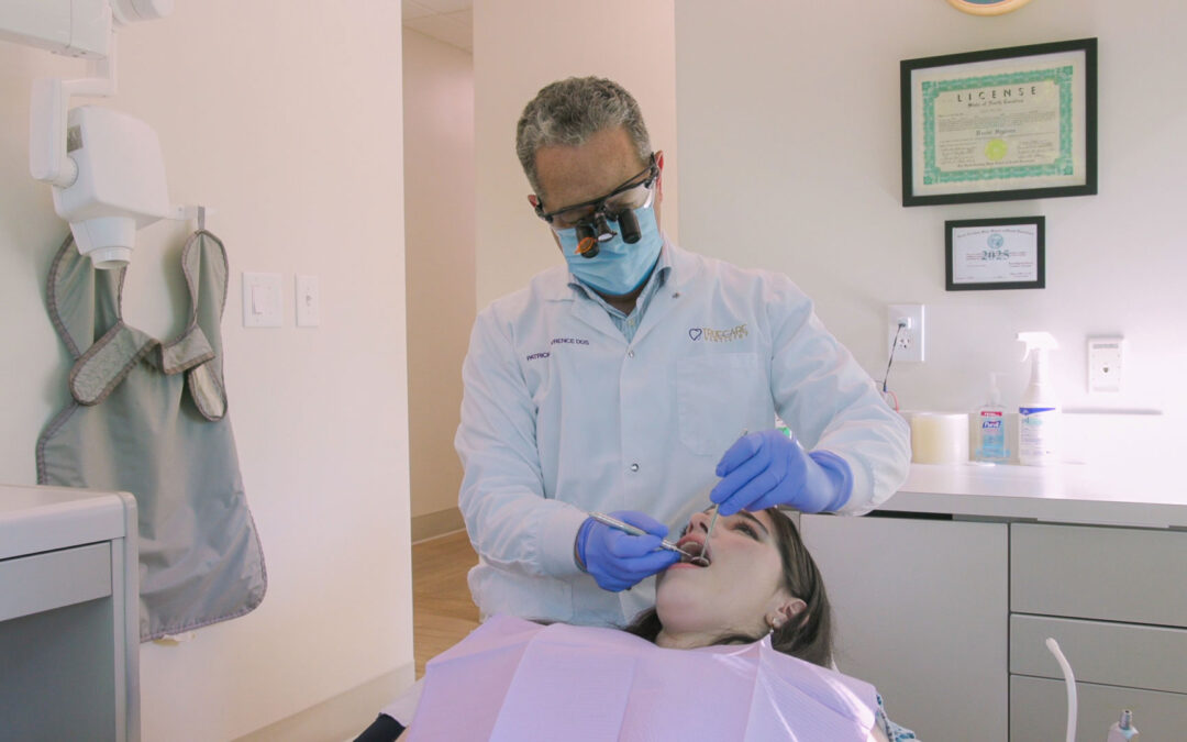 Dentist examining a patient's teeth using magnifying loupes at TrueCare Dentistry.
